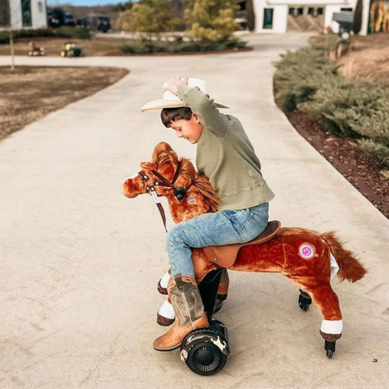 Young child in cowboy hat riding a brown Power Pony outdoors.