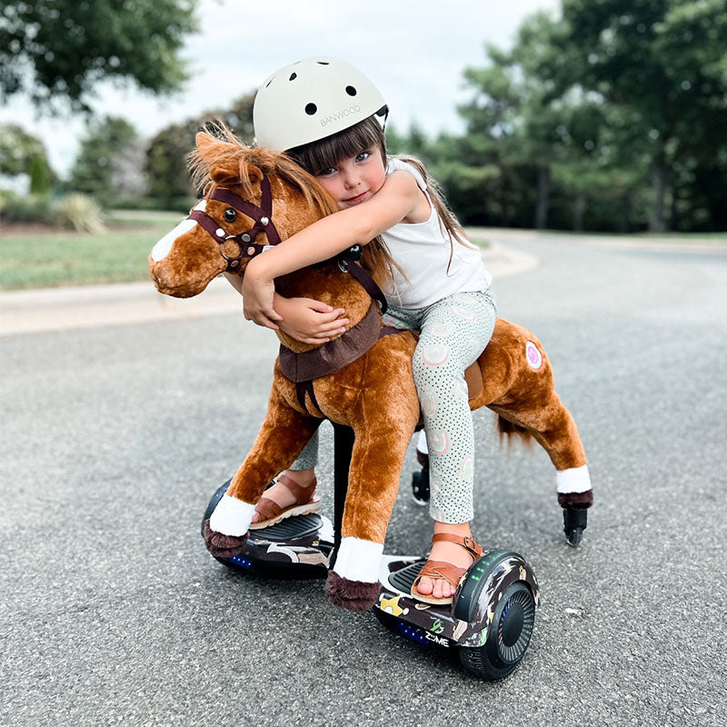 Young girl in a helmet hugging a brown Power Pony on a paved path.