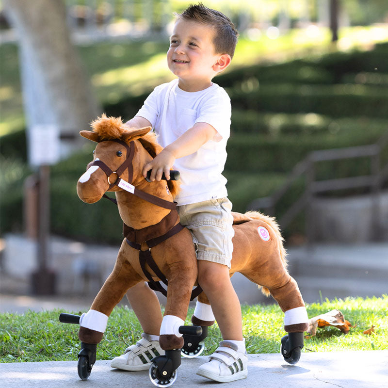 Smiling young boy riding a brown Power Pony outdoors.