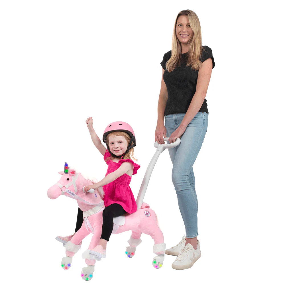 Girl riding a pink Push Pony unicorn with a helmet and colorful lights.